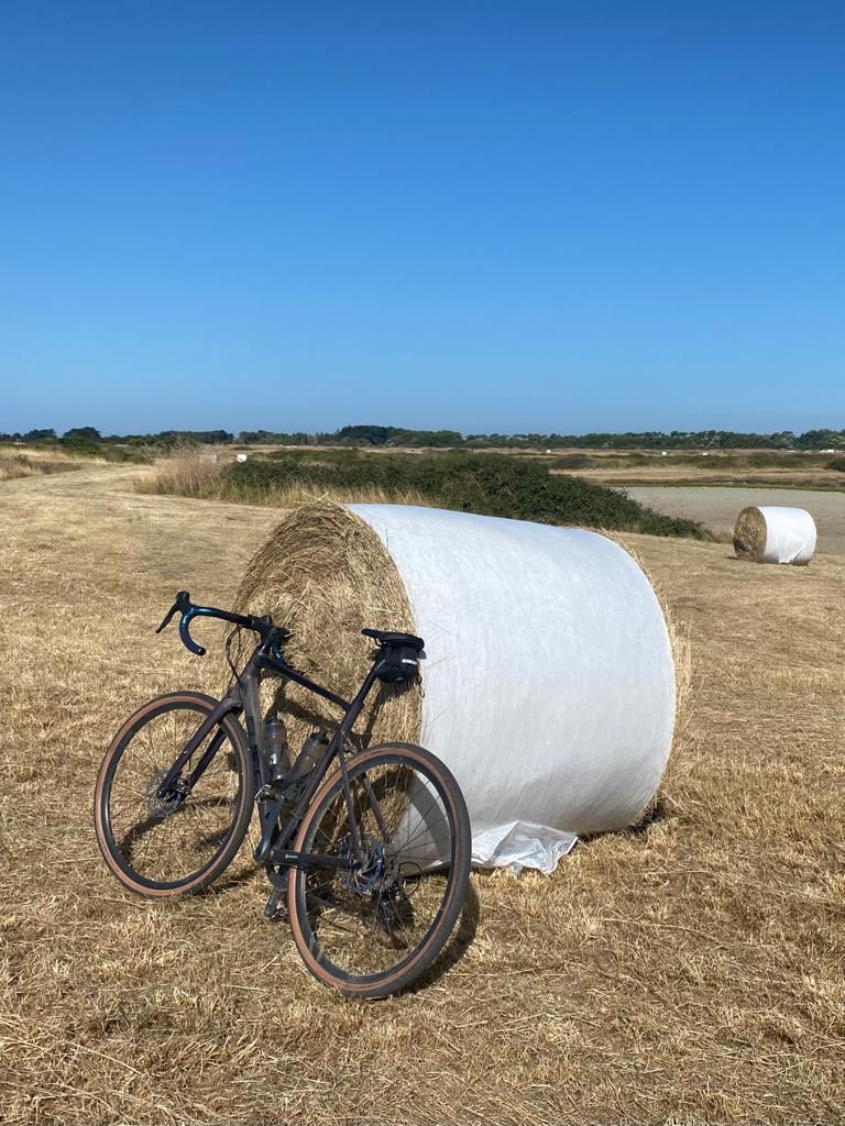 field with bicycle and hay bale against blue sky